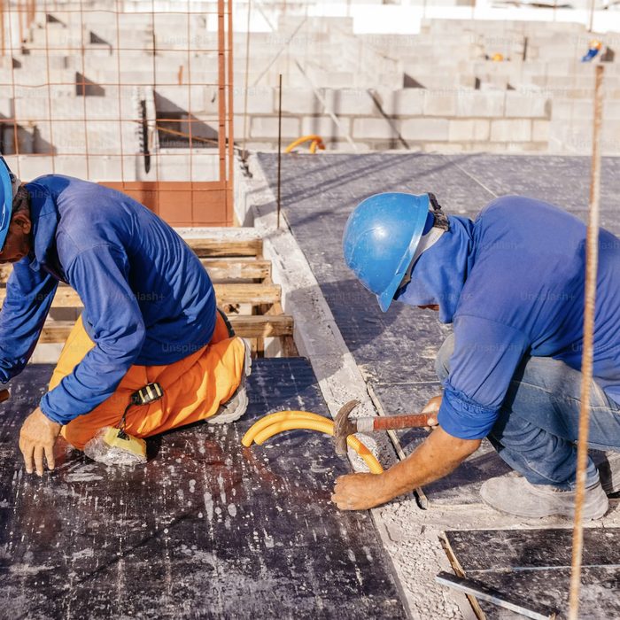 Pekerja memasang lapisan waterproofing atap